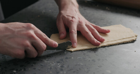 man cutting flat dough with knife