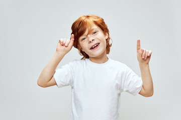  boy with red hair gestures with his hands and index finger up. Copy Space