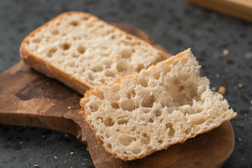 ciabatta bread sliced in half for sandwich on olive board