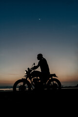Male model on a custom bike during sunset in the beach