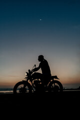 Obraz premium Male model on a custom bike during sunset in the beach