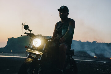 Male model on a custom bike during sunset in the beach