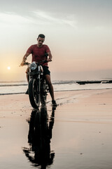 Male model on a custom bike during sunset in the beach