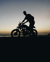 Male model on a custom bike during sunset in the beach