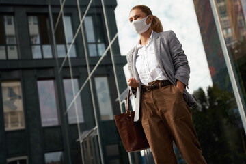 COVID 19 protection. Confident business woman wearing protective face mask standing near office building outdoors