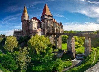 Fototapeta na wymiar Summer view on Corvin castle with bridge over a small river in a sunny day in Romania.