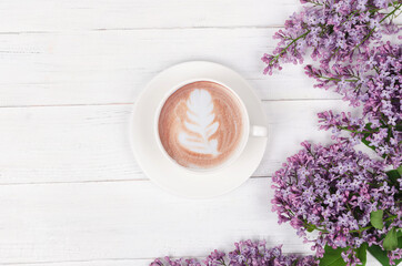 Fototapeta na wymiar Lilac, coffee with latte art on light wooden table. Romantic morning.Flat lay