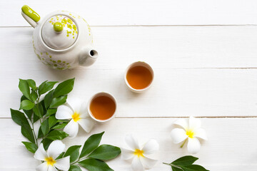 herbal healthy drinks hot tea for health care with teapot ,flowers frangipani arrangement flat lay style on background white wooden