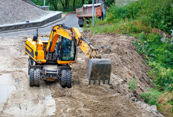 A heavy construction excavator works at a construction site to widen the carriageway.