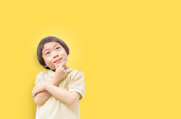 Think of the future of our children concept, Kid post arm on chin looking up with deep thinking on yellow background