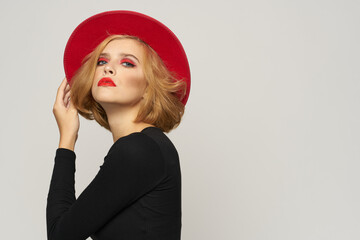 Fashionable woman in red hat black blouse red lips cropped view light background emotions