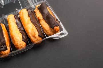 Eclairs with cream filling drenched in chocolate on a black the background
