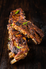 Grilled pork spare ribs with rosemary on wooden background.
