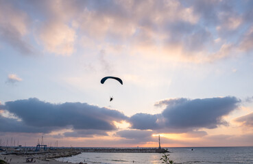 Fototapeta na wymiar Motorized paraglider in amazing sunset sky above Ashkelon`s Marina