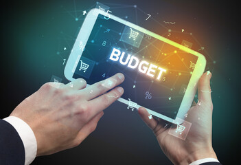 Close-up of a hand holding tablet with BUDGET inscription, online shopping concept