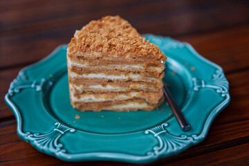 An appetizing piece of Napoleon cake on a blue plate. Close-up.