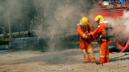 Firefighter fighting with flame using fire hose chemical water foam spray engine. Fireman wear hard hat, body safe suit uniform for protection. Rescue training in fire fighting extinguisher