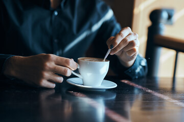 Cup of coffee on the table with white rice and a teaspoon of cafe mens hands.