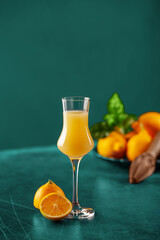 Limoncello in glass, sweet Italian lemon liqueur, traditional strong alcoholic drink and lemons on the color background.