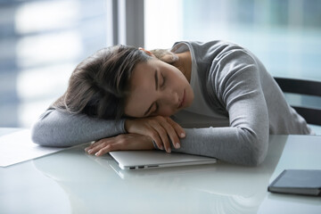 Tired exhausted young businesswoman falling asleep at work desk, suffering from lack of sleep and...