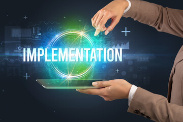 Close-up of a touchscreen with IMPLEMENTATION inscription, new technology concept