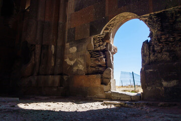 Eastern gates of Cathedral of Ani, medieval city Ani, near Kars, Turkey. There are shown interiors with damaged walls & remains of ornaments. Shiny bright day is outside the building
