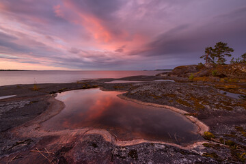 Obraz na płótnie Canvas Rocky shore of the orthern lake at sunset, lake Ladoga