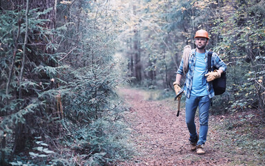 Male lumberjack in the forest. A professional woodcutter inspects trees for felling.