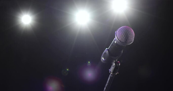 Camera in motion around concert microphone. Professional microphone on stage for record or speak to audience in dark in the spotlight. Musical instrument concept, vocal equipment.