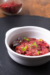 French Food gesiers de poulets confits sous vide Chicken Gizzard Confit in white ceramic cup on black slate board with copy space