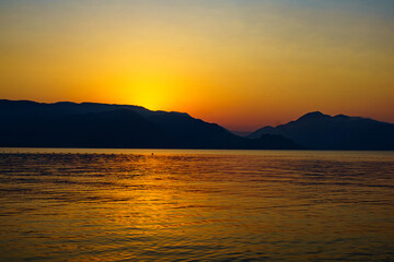 Naklejka premium the sun rises over the mountains and the sea