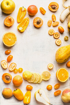 Frame of various yellow fruits and vegetables on white background. Top view. Halves of yellow fruits
