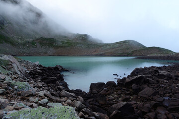 Alpine lake in the clouds. Alpine lake Giybashkel (3240 meters above sea level), Pastushiy pass (3244 meters above sea level), Caucasus.