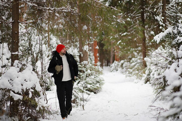 A man travels with a backpack. Winter hike in the forest. Tourist on a walk in the winter in the park.