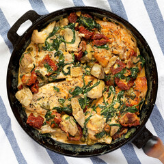 Homemade Creamy Tuscan Chicken in a cast-iron pan, top view. Flat lay, overhead, from above.