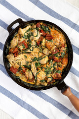 Homemade Creamy Tuscan Chicken in a cast-iron pan, top view. Flat lay, overhead, from above.