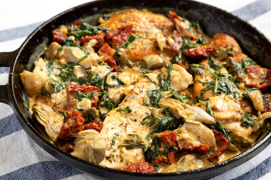 Homemade Creamy Tuscan Chicken in a cast iron pan, side view. Close-up.