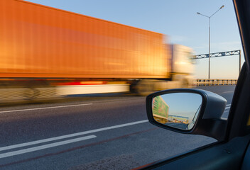 High speed traffic: blurred side view from car window on truck moving fast on highway