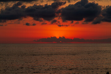 Blood red sunset with dark clouds obscuring the sun over the Black Sea horizon