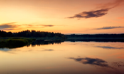 Fototapeta na wymiar Bright beautiful landscape, orange sunset sky over a lake in the forest, reflections in the water