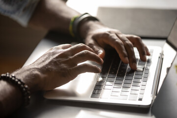 Close up male hands typing on laptop keyboard, African American man working online, blogger...