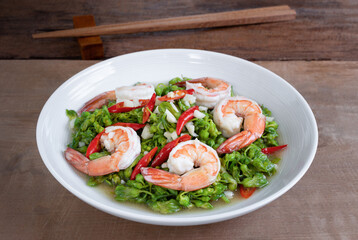 close up of stir fried cowslip creeper with shrimps in a ceramic dish on wooden table. homemade style healthy food concept.