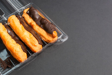 Eclairs with cream filling drenched in chocolate on a black the background