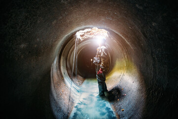 Obraz na płótnie Canvas Sewer tunnel worker examines sewer system damage and wastewater leakage