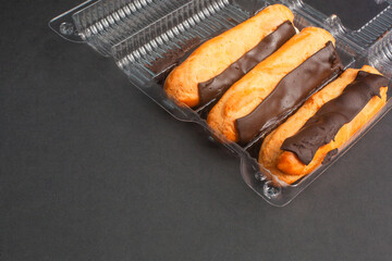 Eclairs with cream filling drenched in chocolate on a black the background