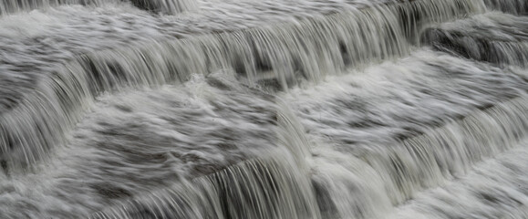 White Water flowing over weir low-level view at long exposure for blurred water effects and textures 