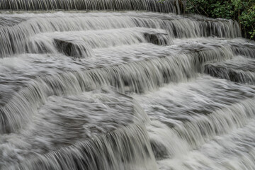 White Water flowing over weir low-level view at long exposure for blurred water effects and...