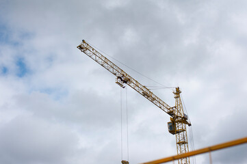 Tower crane for building houses on a background of clouds.