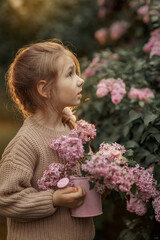Smiling little girl with bouquet of lilac flowers in a spring garden