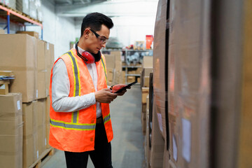 Young male worker of a logistics warehouse with a tablet in his hands is taking inventory of goods